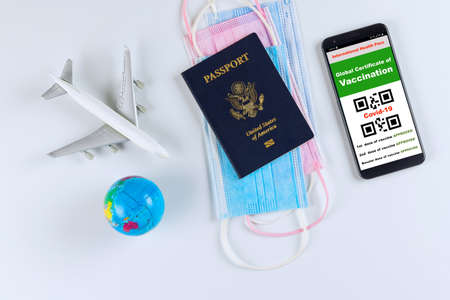 A US passport with a Covid-19 immunization digital document, a face mask an International certificate of immunization for smartphone for travelingの写真素材