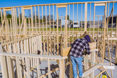Aerial top view of worker in white protective gloves holding plank installing it on household...
