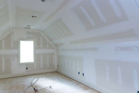 Finishing plastering drywall in ready for paint with new house under constructionの写真素材