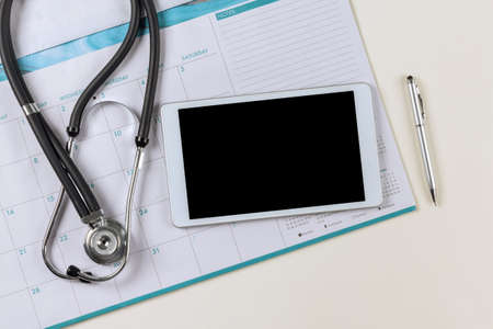 Doctor medical worktable on calendar with stethoscope on digital tableの写真素材
