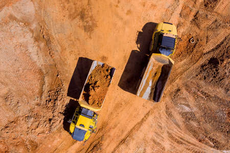 Aerial top view of earth moving heavy equipment at construction site of land preparation process for new residential complexの写真素材