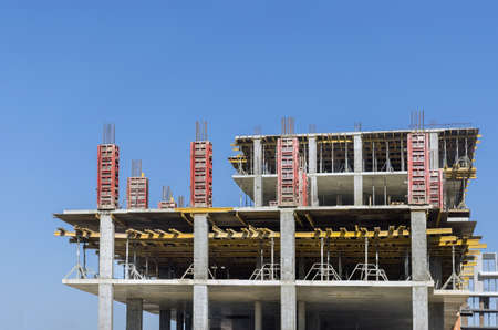 High rise cement building under construction in against blue sky