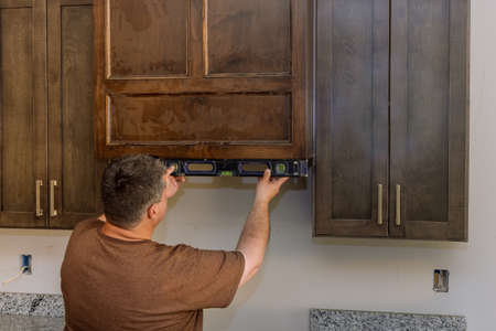 Leveling cabinet furniture for Installation of kitchen in a new house with worker hanging levelの写真素材