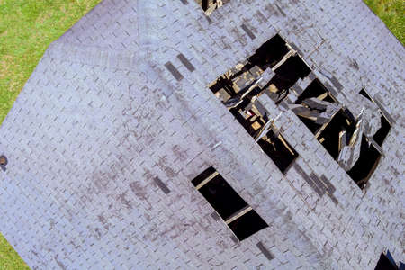 Holes in roof shingles tiled on home from damaged roofing an aerial view