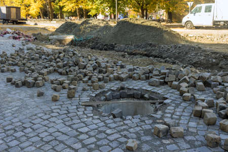 road construction work on preparation for installation of sewer manholes hatches with laying stones on roadの写真素材
