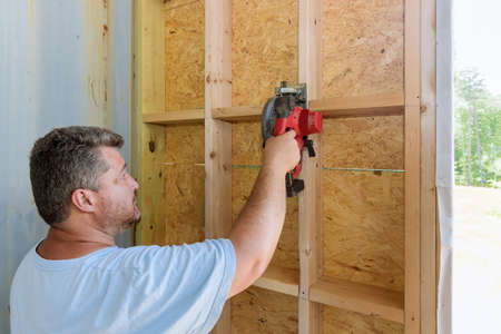 Building contractor worker using hand electric circular saw to cut wooden plank boards on a new home constructionの写真素材