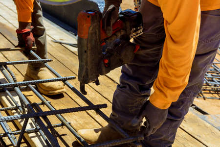 Tool used by construction workers to tie steel bars with wire rods for cement foundations in twisting reinforcementの写真素材