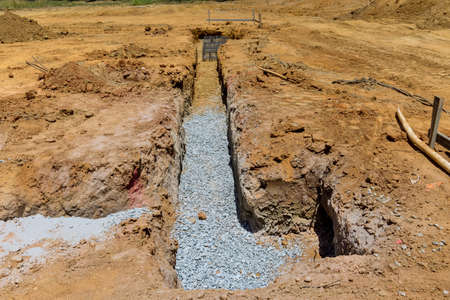 A trench is being dug to a concrete foundation for a new house