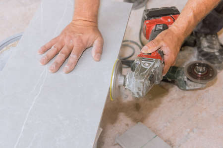 As a worker polishes the cut corner tiles on an angle grinder, he uses a diamond disc polisherの写真素材