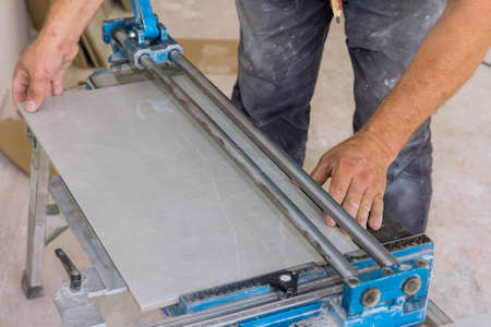 Using manual tools equipment, a construction worker cuts the ceramic tile using manual tools for...