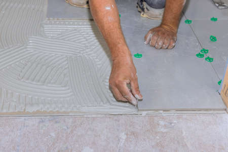 With home construction work, ceramic floor tiles are placed on an adhesive surface in renovation...