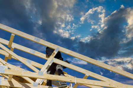 Roofer working with framing installing the roof truss wood of workers nailing wood beams on house...