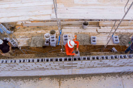 Scaffolding construction site with aerated concrete block wall is being mounted by a mason man of...