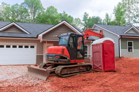 It is near the new house that is being built that the excavator and the portable toilet are located...