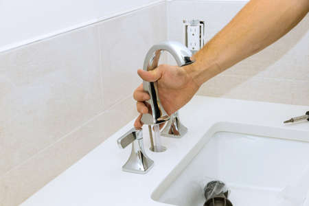The plumber at work assembles and installs the water faucet in the bathroomの写真素材