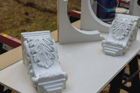 A worker paints wooden corbels for support countertop to kitchen island with using paintbrushの写真素材