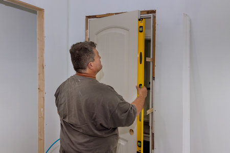 An employee leveling interior doors of new house during installation the doors is checking whether...