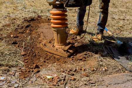 Vibratory plate tamping machine compactor tool jumps from tamping machine compactor tool when compacting to ground in construction siteの写真素材