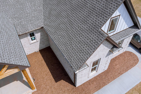 Roof of newly built house is being covered with asphalt shingles during construction while house is...