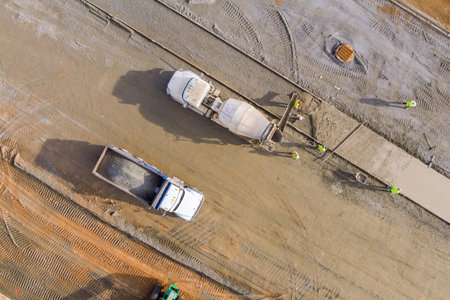 There is concrete mixer truck that pouring concrete mortar to sidewalk workers while construction is...