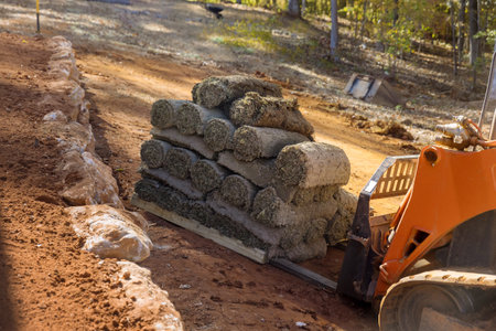 Construction site boom lift is used unload turf rolls from pallets for landscaping in order to lay green grass turf.の写真素材
