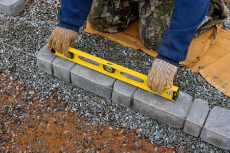 In process of laying stones pathway paving, professional paver worker is performing work.