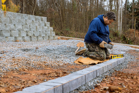 Construction worker installing concrete pavers stones for road sidewalk as part of construction...