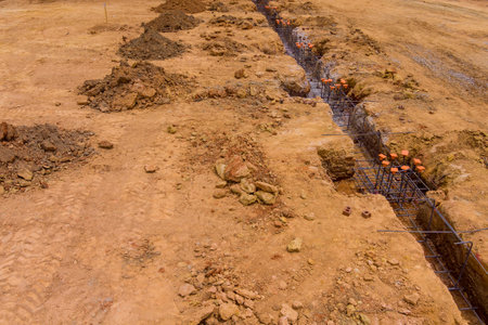 Working on construction site to install steel in trench in order to build house foundationの写真素材