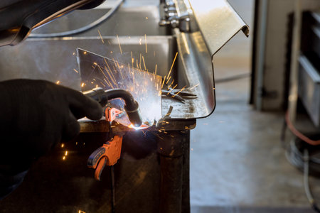 Worker working welding metal with sparkle using welding machine semi automatic argon gas shielded...