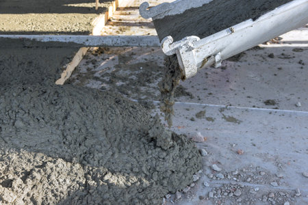 Concrete mixing truck pours concrete for surrounding pavement of newly constructed home on construction siteの写真素材