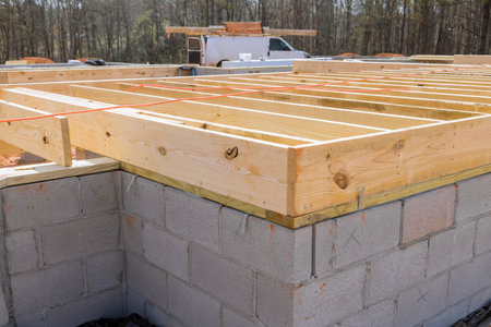 New custom home installation of wood floor joists trusses on concrete block foundation