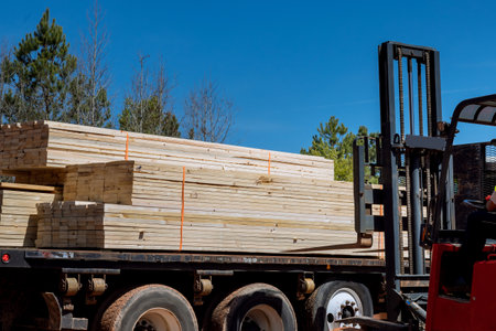 An unloading of wooden building materials on construction site is performed by lift manipulator
