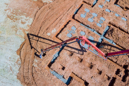Contractor worker pours concrete into house foundation using concrete pumpの写真素材