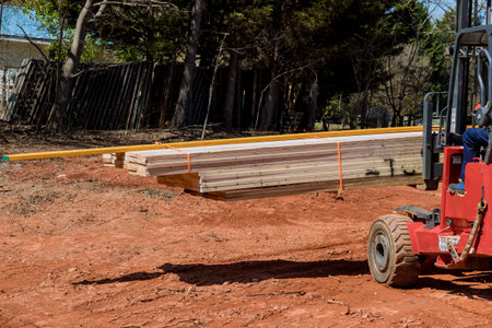 Using lift manipulator construction site worker unloads delivery of wooden building material
