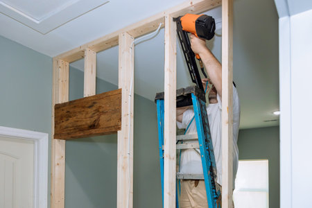 An air hammer is being used by builder to nail wooden beams to housing frameworks so that they can be constructedの写真素材