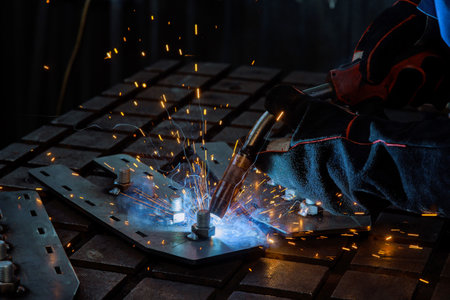 There is workplace where worker is welding steel at work there is a spark lighting up smoke in...