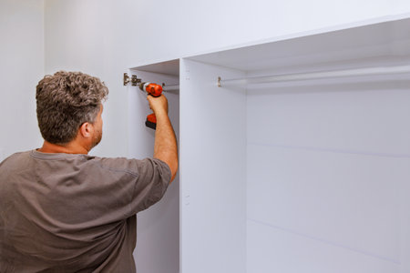 Carpenter working on assembling furniture closet cabinets that needed to be installed in roomの写真素材