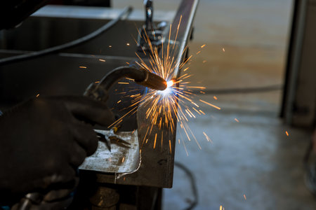 Professional heavy industry worker in protective mask argon welds steel an factory