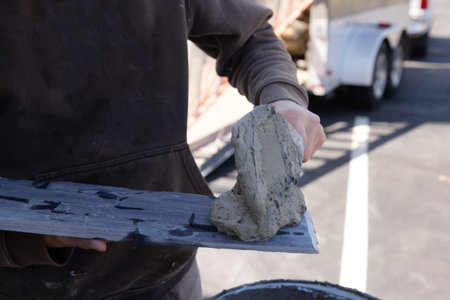 Spreading wet cement adhesive before applying tiles installation with trowel tools by worker