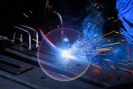 Using an argon torch to weld steel and factory items with professional heavy industry worker wearing...