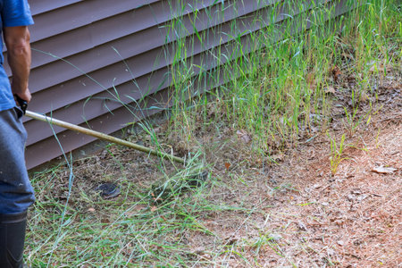 Trimming grass on lawn around residential building with lawn mower is job of worker lawn mower.