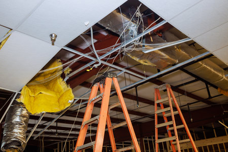 Within construction complex, ceiling works are conducted alongside dismantling of old ceiling during...