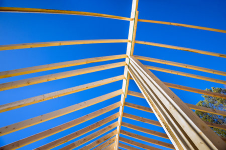 Using wood frame trusses for roof construction on new house is method that uses support beams