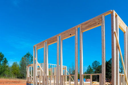 Construction work in progress on an unfinished house with wooden framing beams