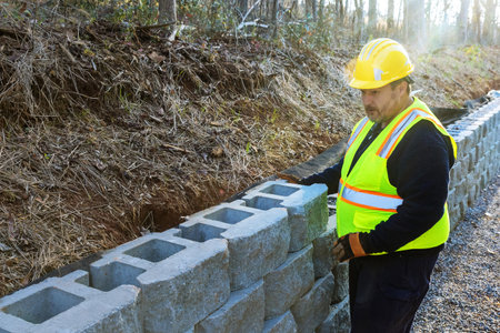 As construction worker mounting retaining wall from, concrete block to ensure its proper placement