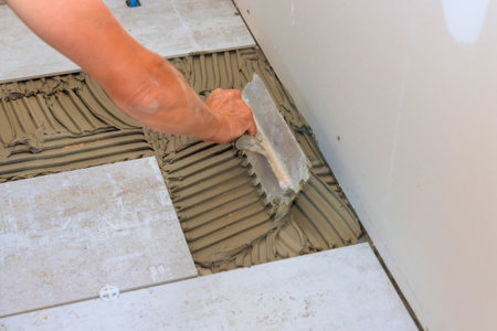 Troweling adhesive onto concrete floor in preparation for laying floor tile.の写真素材