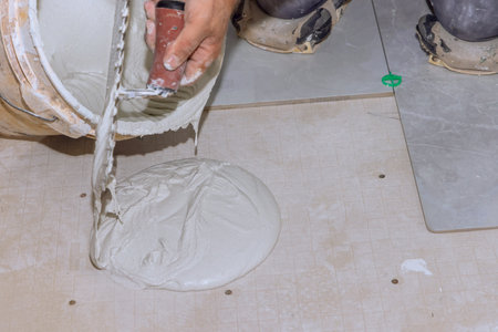 An adhesive mortar cement plaster surface is prepared for installation of ceramic tiles by tilerの写真素材
