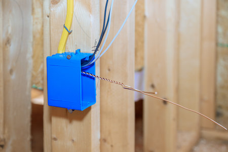 Plastic electrical switch box with wires at wooden frame beams on wallの写真素材