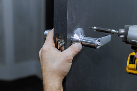 Screwdriver is used by carpenter to install lock handles in room doorの写真素材