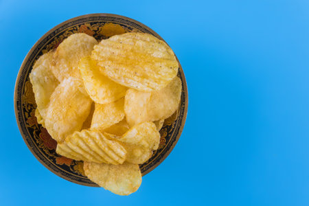 An top view on plate of potato chips at blue backgroundの写真素材